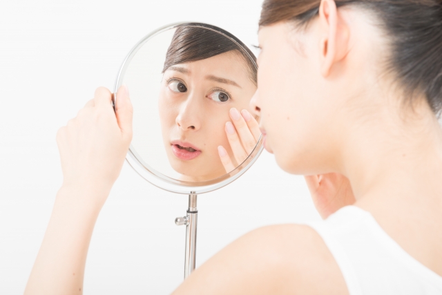 鏡で肌をチェックする女性