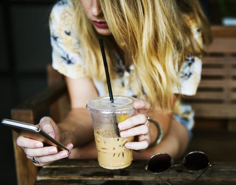 コーヒーと携帯を持つ女性